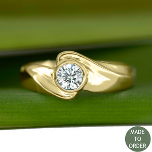 This ring, Timeless, embodies the elegance and harmony of the sea. This is a timeless solitaire ring with a unique flare. The diamond is encircled by a graceful wave in 18K Yellow Gold. The band is finished with a high polish.  Edit alt text